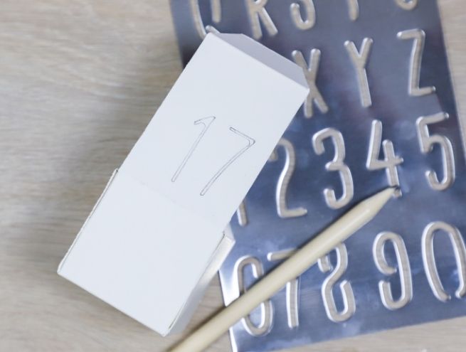 Numérotation des boîtes du calendrier de l’Avent à l’aide de pochoirs et d’un crayon.