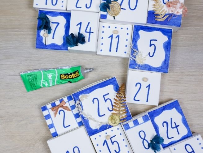 Assemblage final du calendrier de l’Avent herbier, décoré de chiffres bleus et d’éléments naturels.