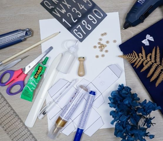 Matériel de loisirs créatifs disposé sur une table pour réaliser un calendrier de l’Avent herbier.