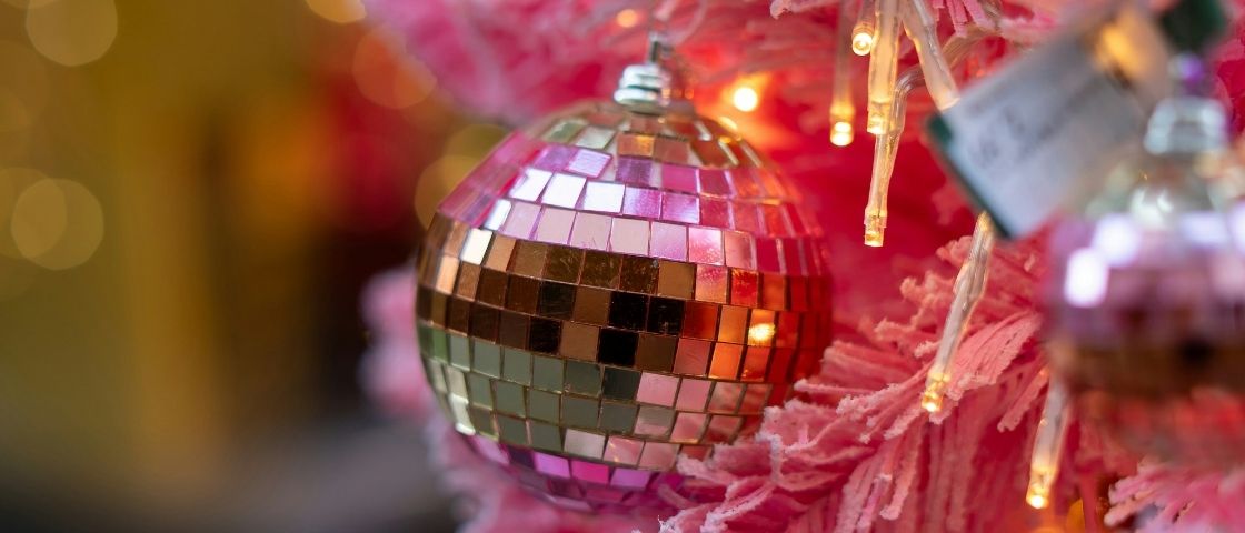 Disco ball hanging from a pink Christmas tree with twinkling lights.