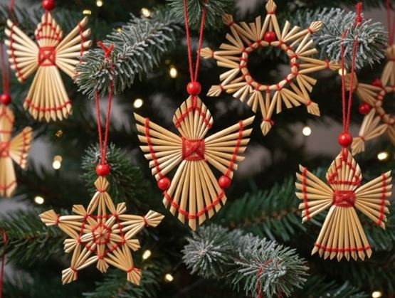 Traditional straw decorations in the shape of angels and stars hanging from a Christmas tree.