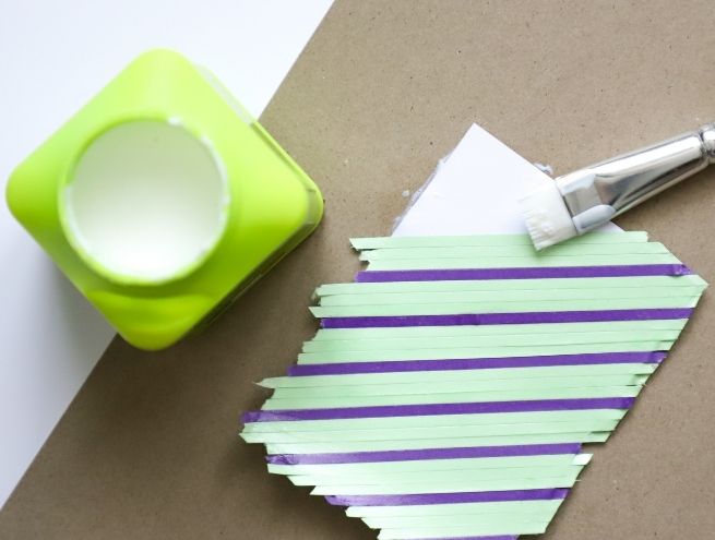 Applying coloured paper strips to a geometric shape for a DIY tutorial