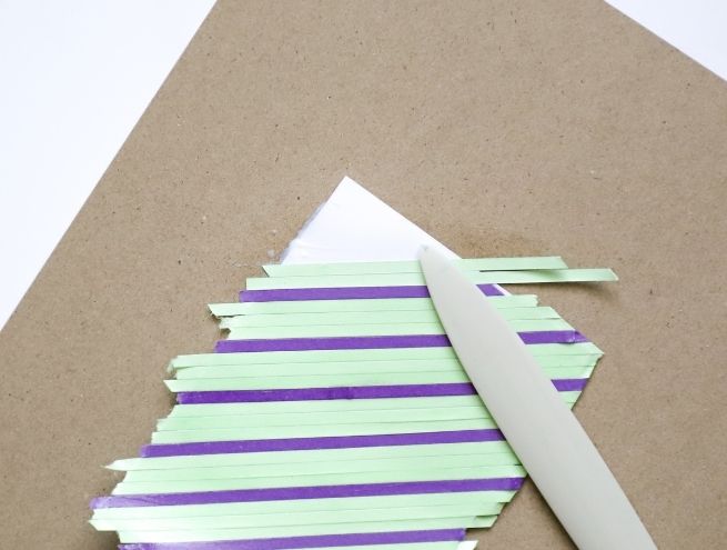 Smoothing coloured paper strips with a flat tool in a DIY workshop