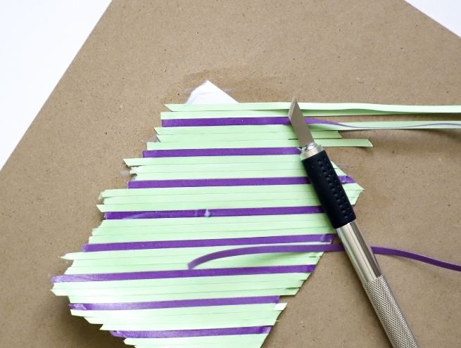 Découpe de bandes de papier colorées avec un cutter pour une création DIY graphique