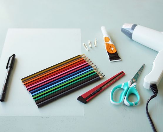 Matériel nécessaire pour créer des broches en plastique : crayons de couleur, ciseaux, colle, épingles.
