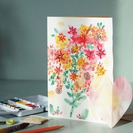 Carte DIY représentant un bouquet de fleurs en aquarelle avec un cœur en papier posé à côté.