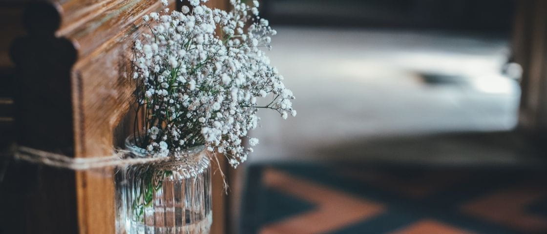 Petit bouquet de gypsophile accroché à un banc d’église avec de la ficelle.