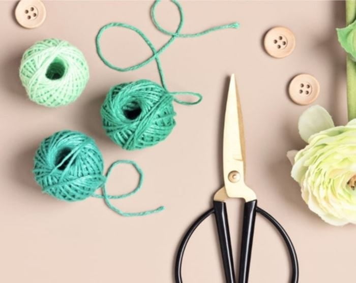 assemblage d'objets, de ciseaux, de bandes de fil, de boutons et de fleurs sur du papier orange